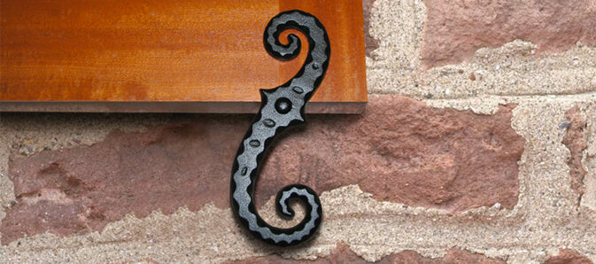 Closeup photo of faux S tieback installed on wood stained shutter.