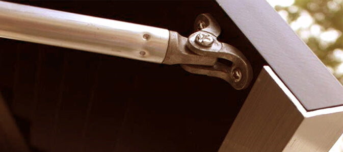 Closeup photo of Bermuda shutter support arm installed on brown Bermuda Shutter.