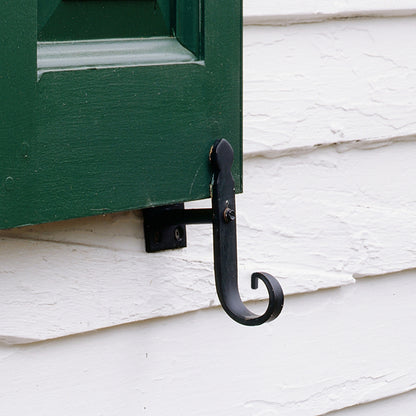 Closeup of Plate Mount Rat Tail Shutter Tiebacks with black powder coating installed on green panel shutter.