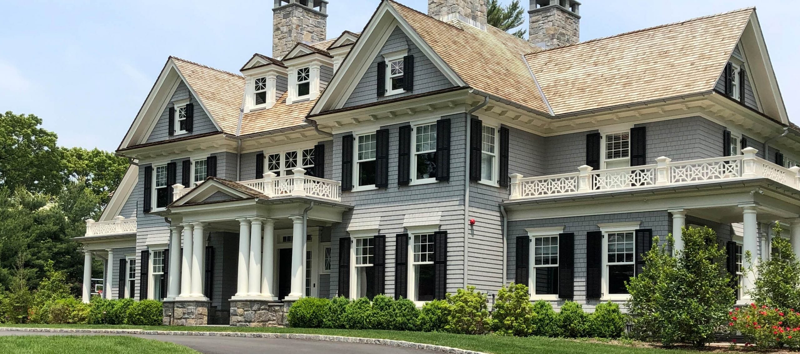 black louver shutters on gray shakes house front angled